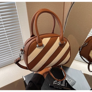 Dettaglio della borsa bowling in similpelle martellata marrone e beige con parti argentate