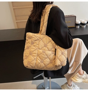 Detail of beige quilted tote bag with floral embroidery and matching charm pouch