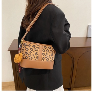 Detail of leopard print bucket bag with brown leather base and cute bear charm accessory