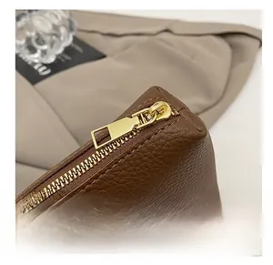 Macro detail of smooth golden zipper and lychee pattern leather on brown bucket bag