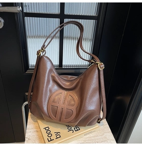 Detail of embossed round logo on brown vintage soft leather hobo bag with dual shoulder straps