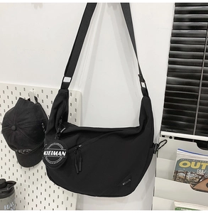 Close-up of black nylon crescent bag with adjustable strap and decorative tag