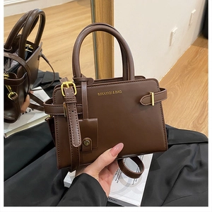 Détail du sac à main en cuir marron foncé avec finitions dorées et reflet miroir