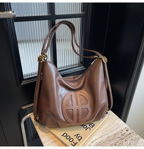 Macro detail of dark brown soft faux leather tote bag with vintage embossed circular logo
