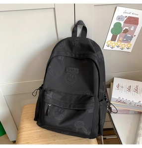 Detailed close-up of a black nylon backpack featuring subtle smile patterns and OK prints