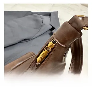 Détail de la fermeture éclair en métal doré avec gravure KOSK sur le sac en cuir marron