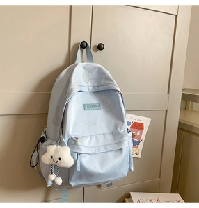 Detail of light blue waterproof nylon school bag featuring cute cartoon graphics and cloud charm