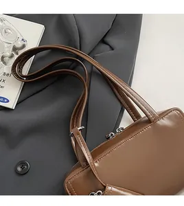 Detail view of brown glossy faux leather shoulder bag with double straps and metal zipper