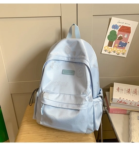 Close-up of light blue nylon backpack featuring cute cartoon graffiti and side storage pocket