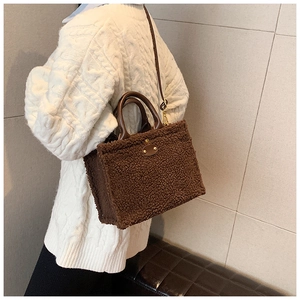 Detail view of large dark brown plush tote bag with leather straps on a model