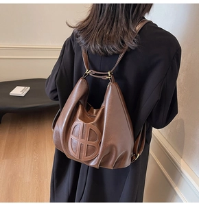 Detail shot of brown soft leather tote bag with circular logo and slim straps