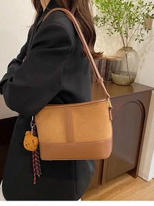Leopard print bucket bag with adjustable strap and bear charm on a model in a suit