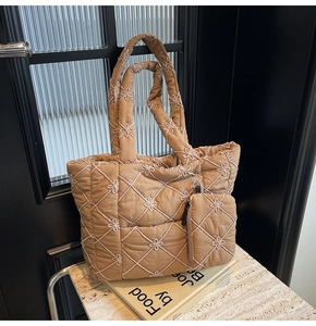 Detailed embroidery and diamond quilting texture on a brown padded cotton tote bag