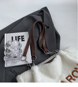 Detail of white plush tote bag showing brown leather strap and silver metal chain links