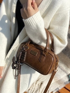 Brown vintage pillow bag with gold lettering and cute charms on white knit sweater