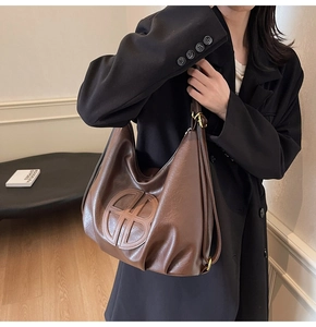 Close-up of vintage dark brown faux leather tote bag with embossed geometric logo detail