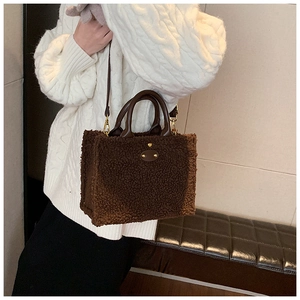 Close-up of brown plush teddy fabric tote bag with leather handles and gold rivet detail