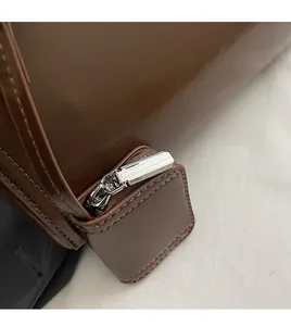 Detailed close-up of premium silver zipper and stitching on dark brown leather shoulder bag