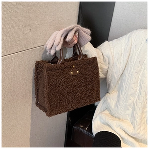 Close-up of brown plush tote bag with leather handles shown in a winter fashion context