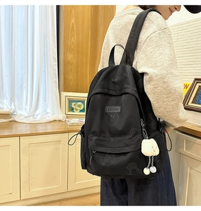 Detail of black waterproof nylon backpack with street graffiti pattern and plush bunny charm