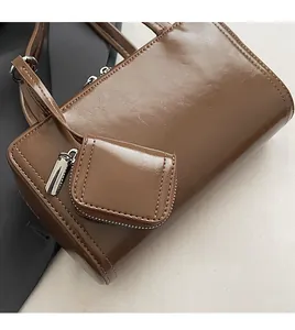 Close-up of dark brown glossy shoulder bag with a matching detachable square pouch detail