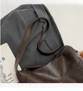 Detail of dark brown faux leather tote bag showing soft texture and wide shoulder strap