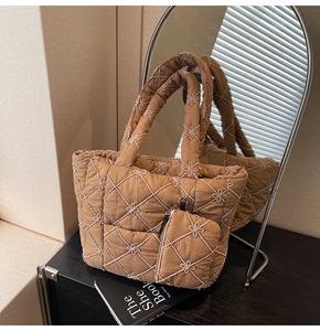 Detail of quilted tote bag featuring floral embroidery and matching small pouch in brown