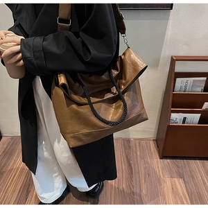 Grand sac cabas marron avec poignées tressées et large bandoulière porté par un mannequin