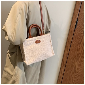 Detail of plush fleece tote bag featuring brown leather straps and vintage oval patch
