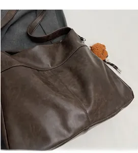 Detail of soft brown PU leather texture and cute plush bear charm on tote bag