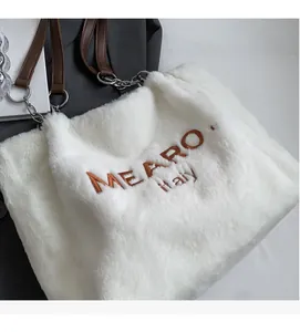 Close-up of white faux fur tote bag with brown MEAROY Italy embroidery and leather strap
