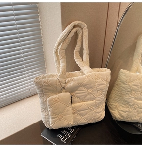 Detail of quilted tote bag with floral embroidery and matching mini zipper pouch accessory