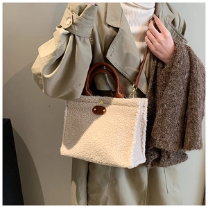 Detail of plush tote bag with quilted fleece texture and brown leather strap on model