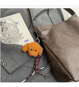 Brown faux shearling teddy bear bag charm with tassel detail on a brown leather tote