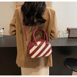 Dettaglio della borsa patchwork rossa e crema indossata, con pelle sintetica martellata