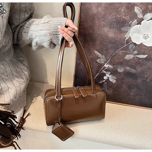 Detailed close-up of retro brown leather shoulder bag with matching mini pendant charm