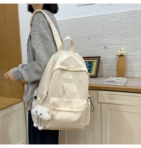 Detail of beige nylon backpack with cute cartoon patterns and plush cloud keychain charm