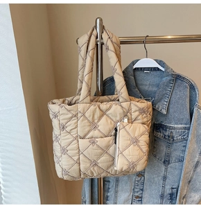 Detail of beige quilted tote bag featuring floral embroidery and matching small pouch