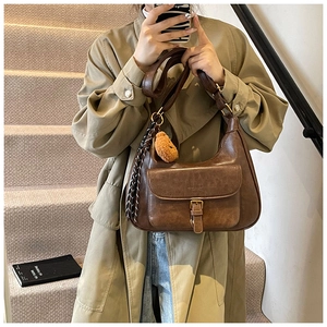 Détail du sac bandoulière marron vintage avec ourson en peluche et pompon tressé