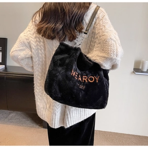 Detail view of black faux fur tote bag with orange embroidery and metal chain strap