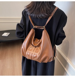 Detail of caramel brown soft leather tote bag with circular embossed logo on luxury hobo style