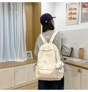 Detail of cute cream-colored backpack with cartoon prints and plush cloud charm