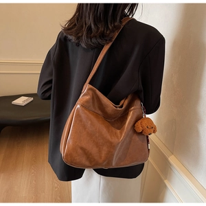 Detailed back view of a large brown vintage leather hobo bag with a teddy bear charm