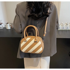 Vista dettagliata di una mini borsa Boston a righe abbinata a blazer grigio e vestito