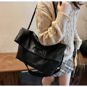 Détail du sac cabas en cuir souple noir avec bandoulière tressée et sangle réglable en nylon