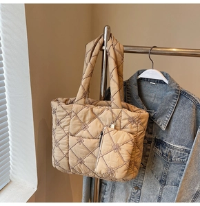 Detail of beige quilted tote bag featuring embroidered floral patterns and small pouch