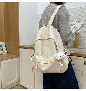 Detail of cream backpack with bunny prints and a soft cloud charm in a cozy indoor setting