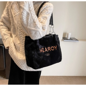 Detail of plush black tote bag with orange embroidery and chain shoulder strap
