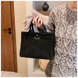 Close-up of black plush tote bag with oval leather patch and gold rivet details