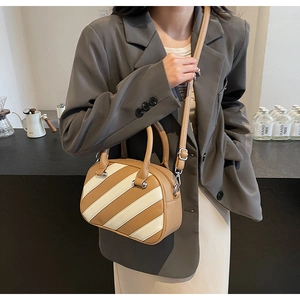 Dettaglio di una borsa patchwork marrone e beige su una modella in blazer